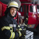 vigile-del-fuoco-maschio-alla-stazione-in-tuta-e-casco