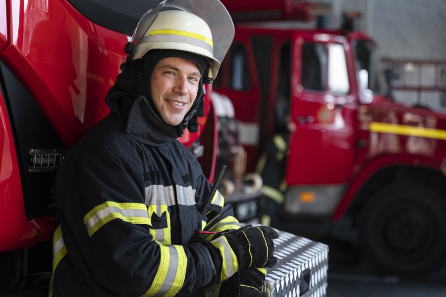 vigile-del-fuoco-maschio-alla-stazione-in-tuta-e-casco