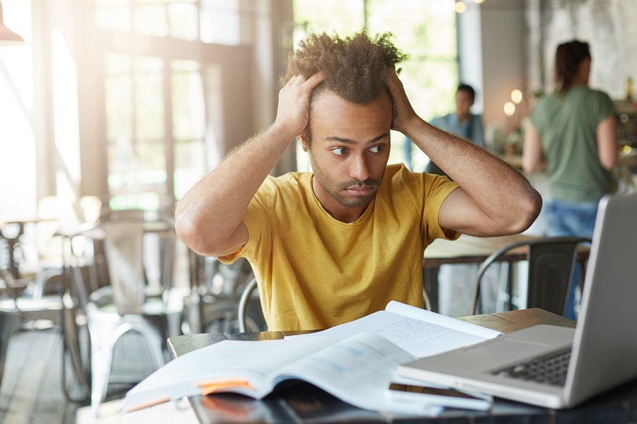 studente-che-si-sente-stressato-tiene-le-mani-sulla-testa-fissa-lo-schermo-del-laptop-in-preda-alla-frustrazione-e-alla-disperazione